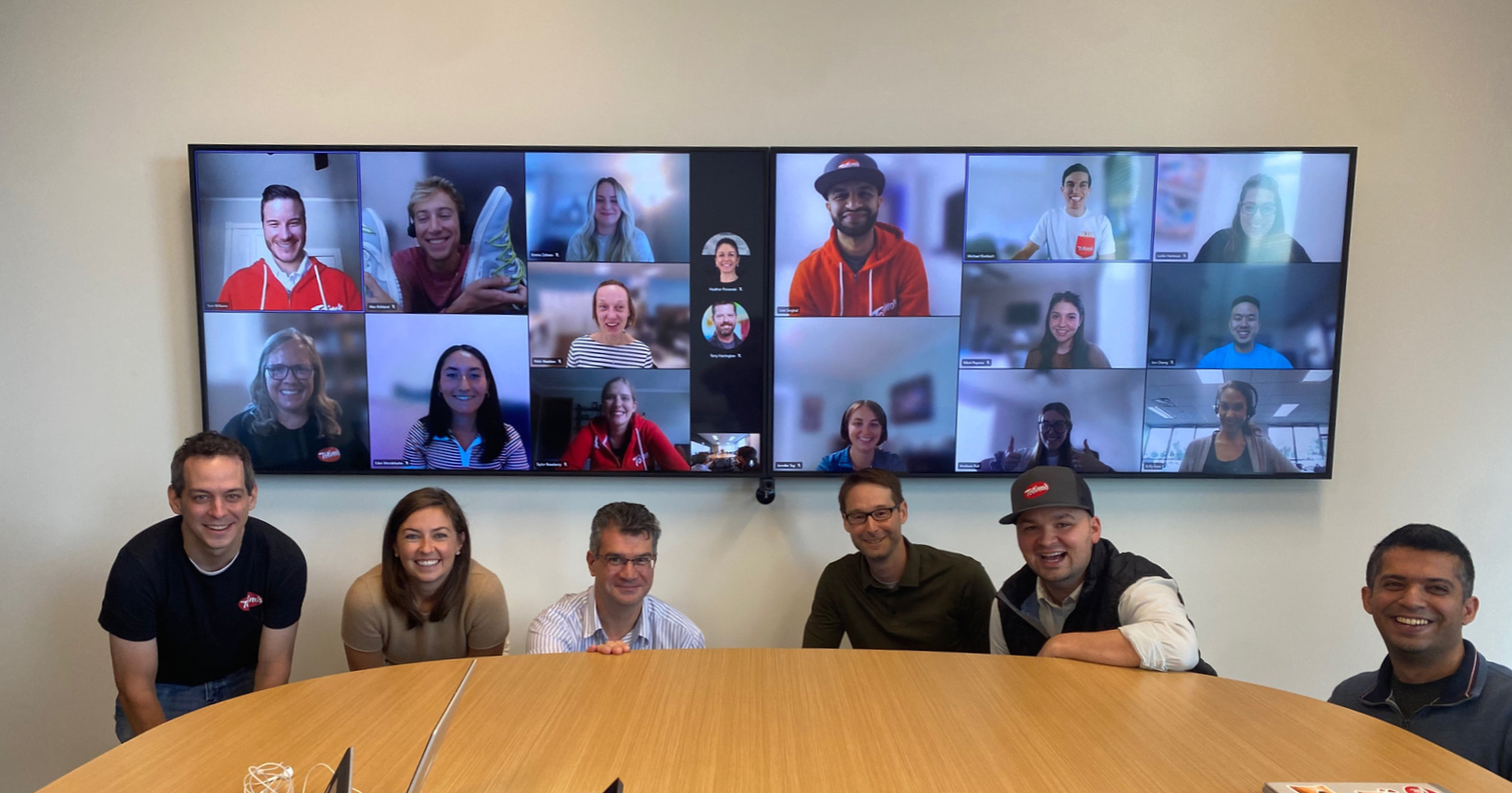 Employee team photo with members in the room and members on the screen