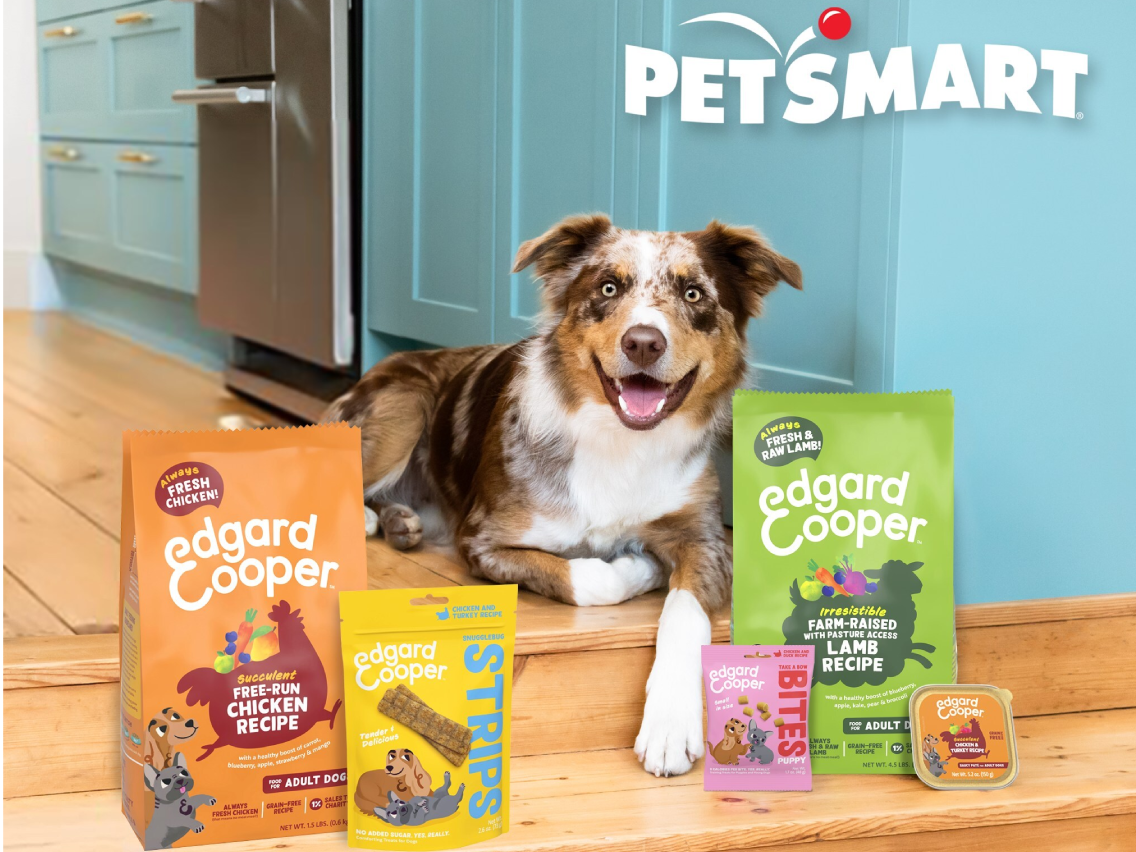 Dog laying on the floor of a blue kitchen surrounded by bags of Edgard & Cooper dog food